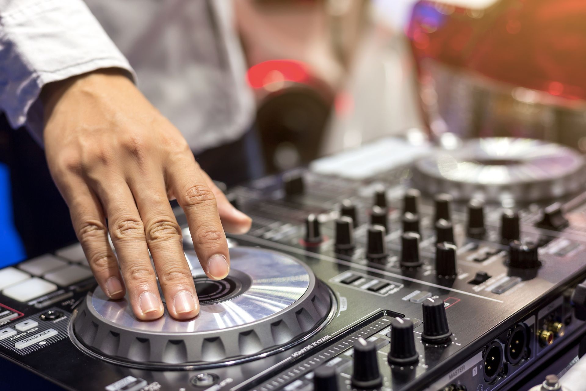 Close up view of  DJ's hand controls on the deck at night. DJ spinning and scratching music in concert using mixing console on a turntable in sound recording studio.